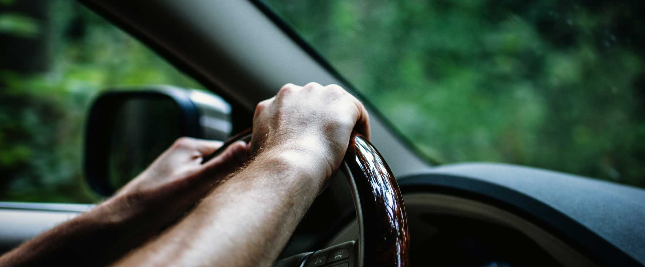 hands gripping car steering wheel